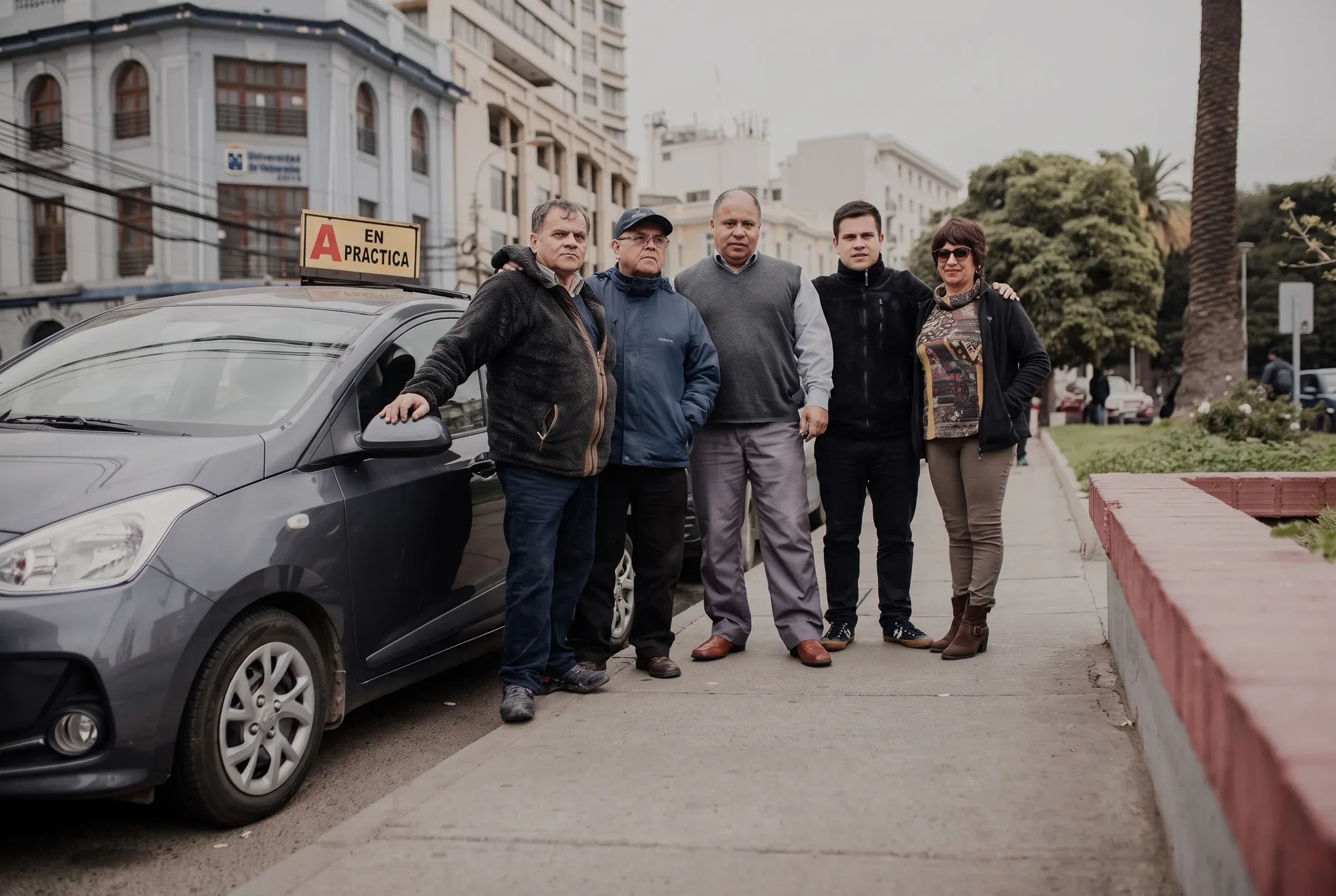 Equipo de instructores de la escuela junto a uno de los autos