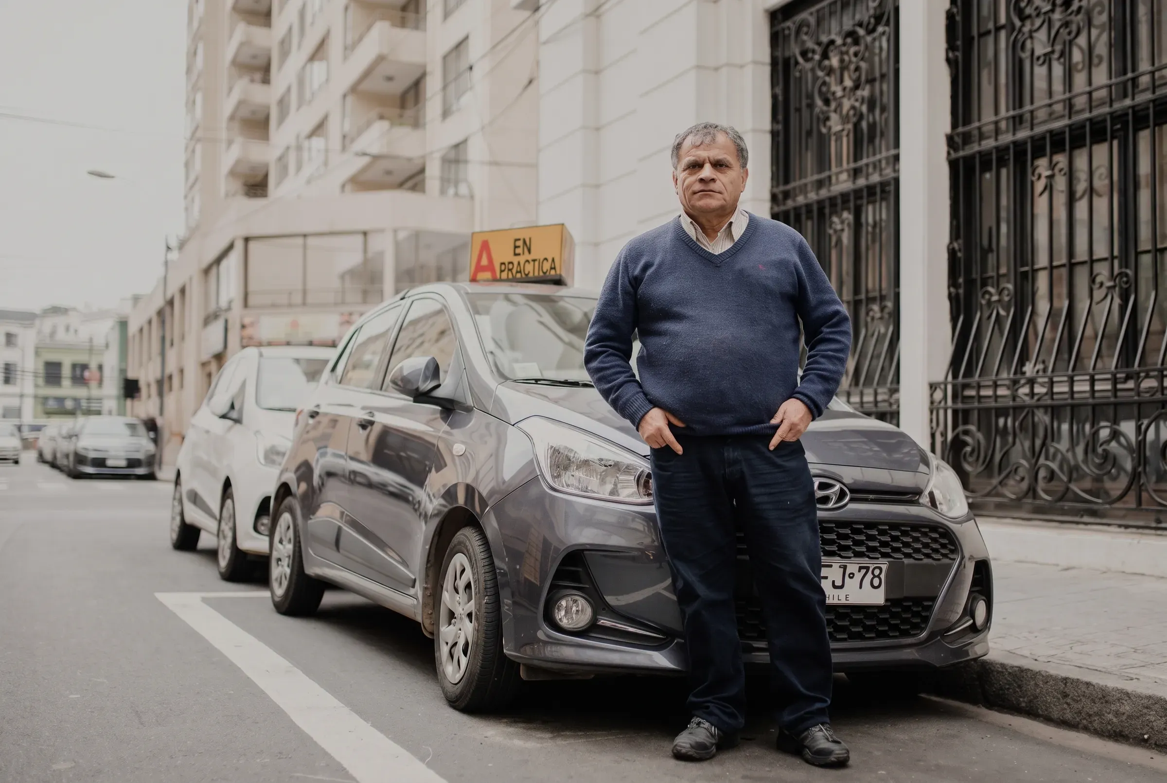 Instructor de pie junto al auto con letrero A en práctica